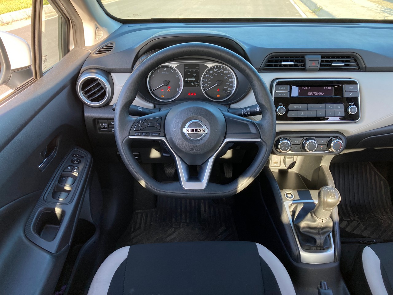 Imagem da visão do motorista no caro Nissan Versa, colocando em perspectiva o volante e o painel do veículo. 