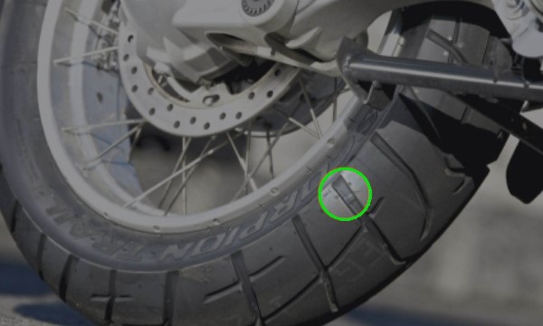Foto mostrando o TWI no pneu de uma moto.