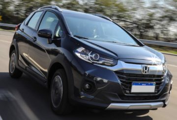 Foto de um Honda WR-V preto sendo dirigido em uma rua de asfalto. Ao fundo é possível ver algumas árvores em movimento.
