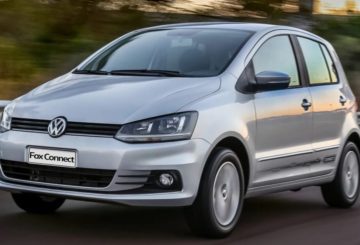 Foto da dianteira de um Volkswagen Fox G3 na cor prata. Na foto, o carro está sendo dirigido na estrada e ao fundo é possível ver algumas árvores.