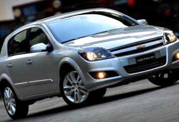 Foto tirada na diagonal de um Chevrolet Vectra GT prateado estacionado na rua.