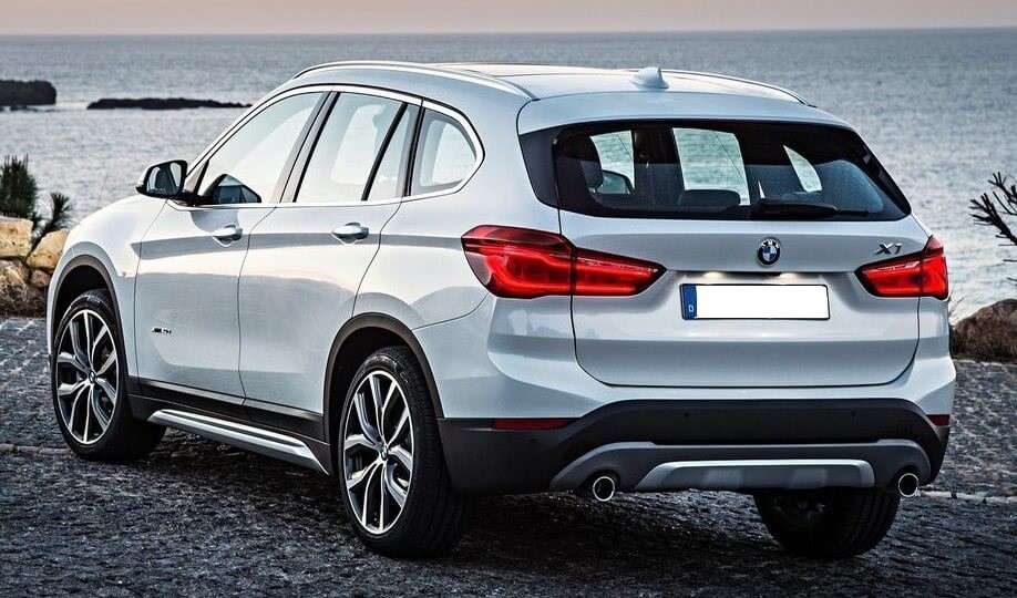 Foto da traseira de um BMW X1 G2 branco. Na foto, o carro está estacionado em frente a um lago.