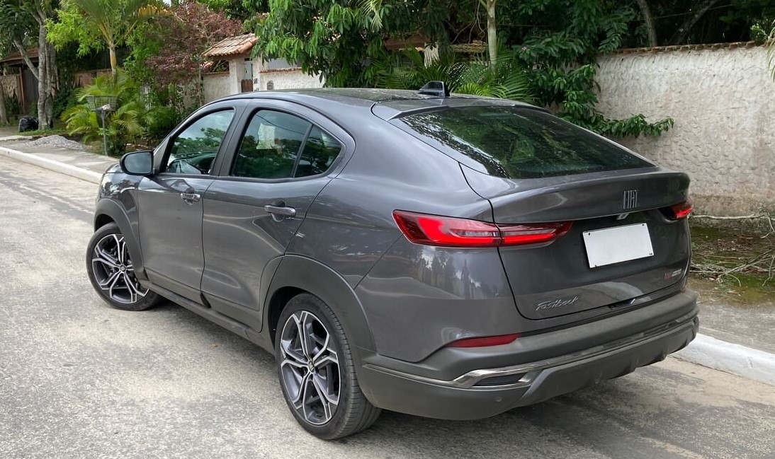 Foto da traseira de um Fiat Fastback Limited Edition cinza que está estacionado em frente ao muro de uma casa.