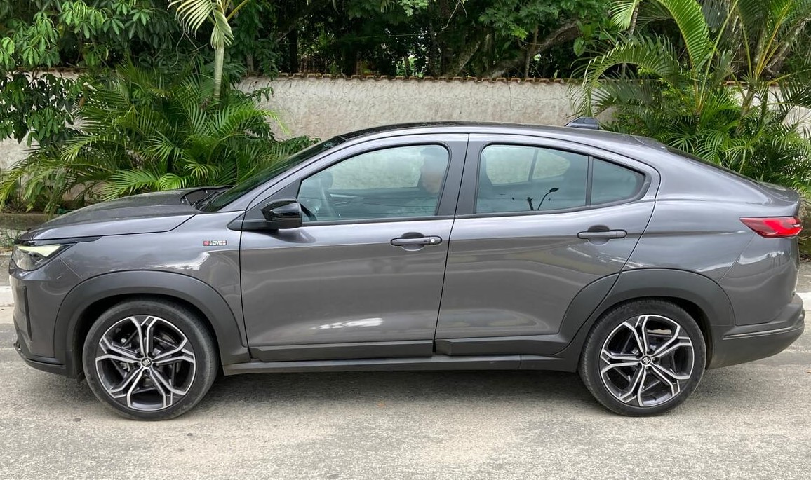 Foto da lateral esquerda de um Fiat Fastback Limited Edition cinza, que está estacionado em frente ao muro de uma casa.