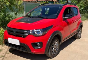 Foto mostrando a dianteira de um Fiat Mobi 2023 vermelho que está estacionado em frente a um muro verde claro