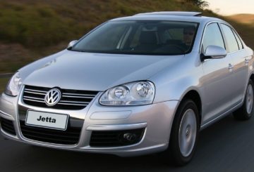 Foto mostrando a dianteira de um Volkswagen Jetta G5 prateado sendo dirigido em uma estrada de asfalto.