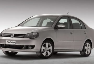 Foto feita em estúdio mostrando a diagonal esquerda de um Volkswagen Polo Sedan prateado.