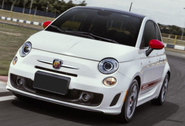 Foto mostrando a dianteira de um Fiat 500 branco, da versão abarth, sendo dirigido em uma rua de asfalto.