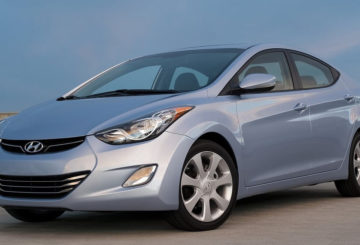 Foto mostrando a dianteira de um Hyundai Elantra prateado estacionado em uma rua de asfalto.