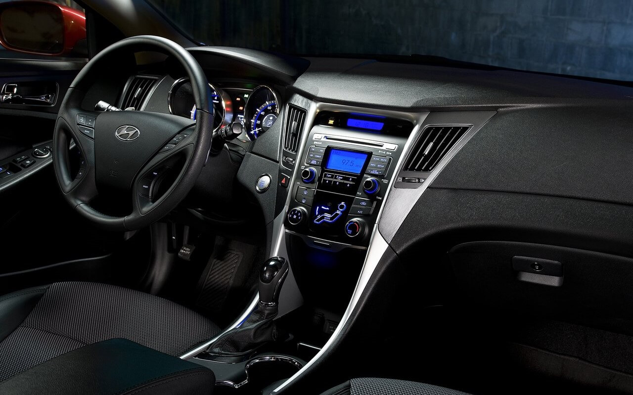 Foto mostrando o painel do carro, o volante, o computador de bordo, o rádio, as saídas e os comandos de ar e o câmbio.