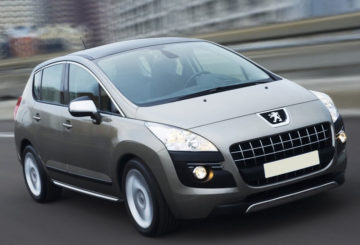 Foto mostrando a dianteira de um Peugeot 3008 G1 cinza sendo dirigido em uma estrada de asfalto.