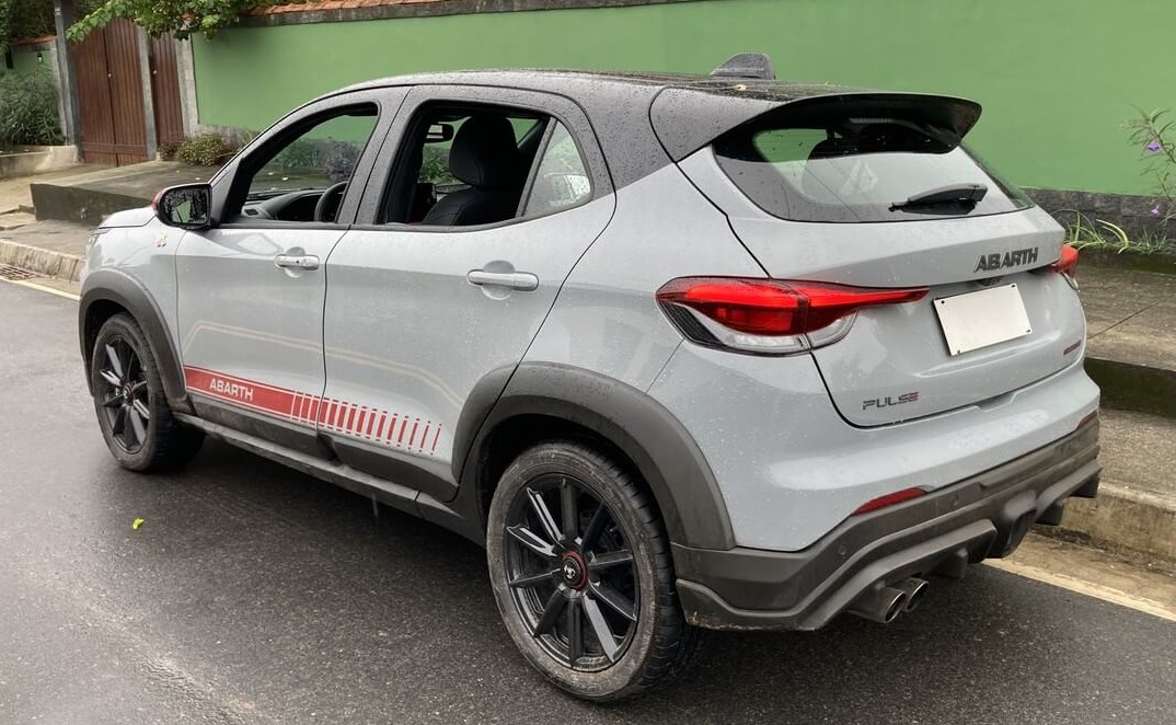 Foto mostrando a traseira de um Fiat Pulse Abarth 2023 cinza claro com detalhes em vermelho e rodas pretas.