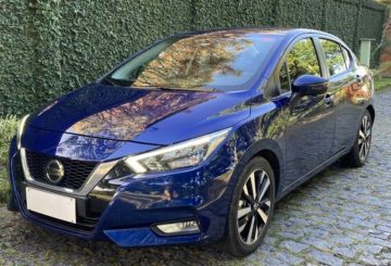 Foto da dianteira de um Nissan Versa 2023 azul estacionado em uma rua de paralelepípedos