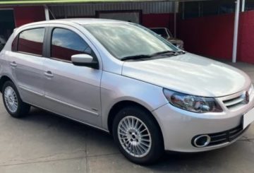 Foto mostrando a diagonal direita de um Volkswagen Gol 2010 G5 prateado estacionado em frente a uma loja.