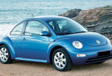 foto mostrando a dianteira de um Volkswagen New Beetle azul, estacionado em uma praia.