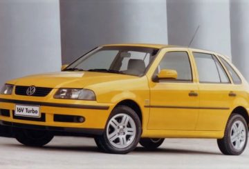 Foto feita em estúdio mostrando a dianteira e a lateral esquerda de um Volkswagen Gol G3 Sport amarelo