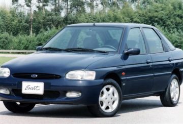 Foto mostrando a dianteira de um Ford Escort G4 azul estacionado em uma rua de asfalto.