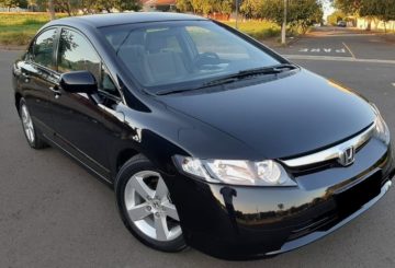 Foto mostrando a diagonal direita de um Honda Civic LXS 2008 preto estacionado em uma rua de asfalto.