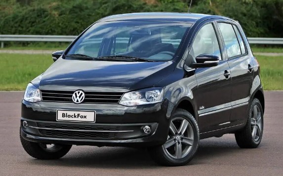 Foto mostrando a dianteira de um VW Fox 2011 preto estacionado em uma rua de asfalto.