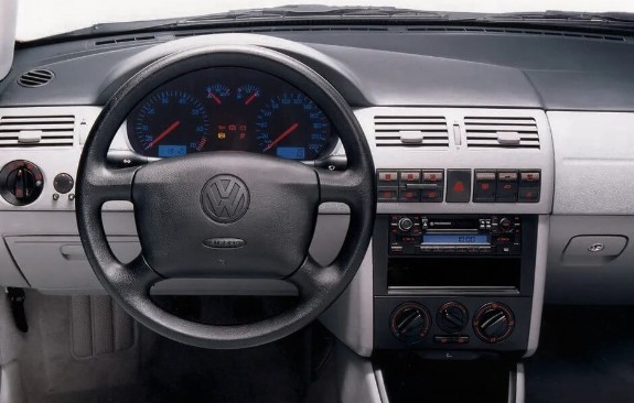 Foto mostrando o painel do carro. É possível ver o volante, o computador de bordo, as saídas e os controles do ar e do rádio.