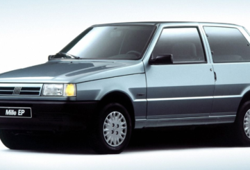 Foto feita em estúdio mostrando a diagonal esquerda de um Fiat Uno EP 1996 azul claro.