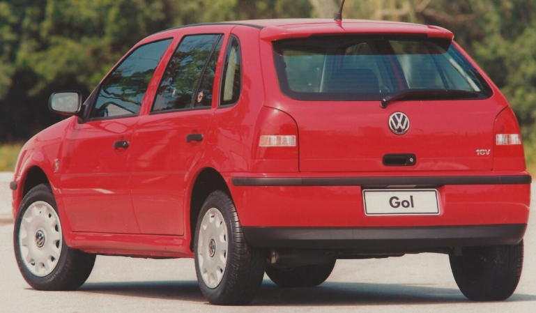 Foto mostrando a traseira de um Volkswagen Gol 2000 vermelho estacionado em uma rua de asfalto.