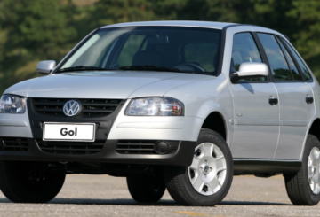 Foto mostrando a diagonal esquerda de um Volkswagen Gol 2006 prateado estacionado em uma rua de asfalto.