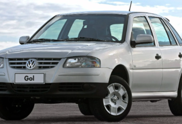 Foto mostrando a diagonal esquerda de um Volkswagen Gol 2007 prateado estacionado em uma rua de asfalto.