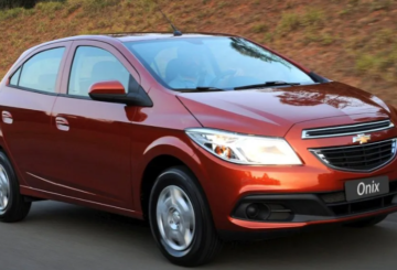 Foto mostrando a diagonal direita de um Chevrolet Onix LT 2015 laranja.