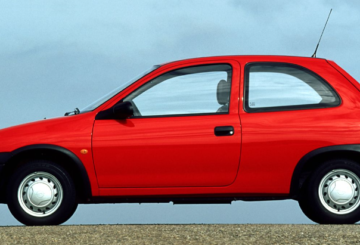 Foto mostrando a lateral esquerda de um Chevrolet Corsa Wind 1996 vermelho estacionado em uma rua de asfalto.
