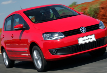 Foto mostrando a dianteira de um Volkswagen Fox 2013 vermelho sendo dirigido em uma rua de asfalto.
