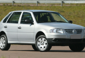 Foto mostrando a diagonal direita de um Volkswagen Gol 2005 prateado estacionado em uma rua de asfalto.