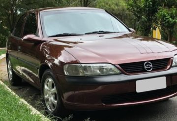 Foto mostrando a dianteira de um Chevrolet Vectra G2 vinho estacionado em uma rua de asfalto.