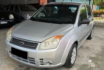 Foto mostrando a dianteira de um Ford Fiesta 2008 prateado estacionado em uma loja.