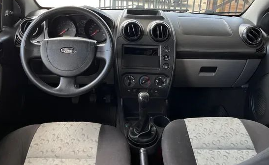 Foto mostrando a cabine do carro. É possível ver o volante, o painel, o ...