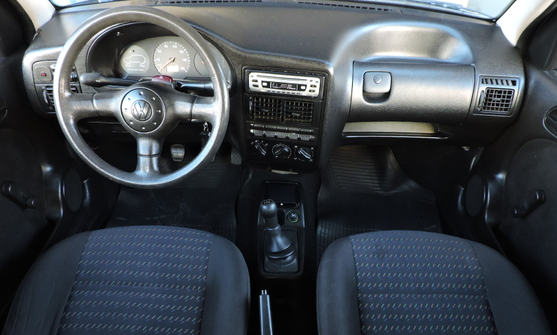 Foto mostrando a cabine do carro. É possível ver o volante, o painel, o ...