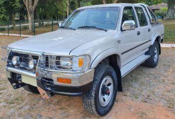 Foto mostrando a dianteira de um Toyota Hilux G6 estacionado em uma rua de pedras.
