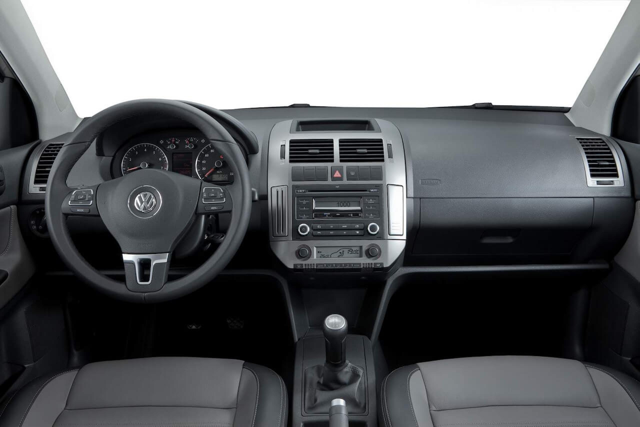 Foto mostrando a cabine do carro. É possível ver o volante, o painel, o câmbio e os assentos dos bancos dianteiros.