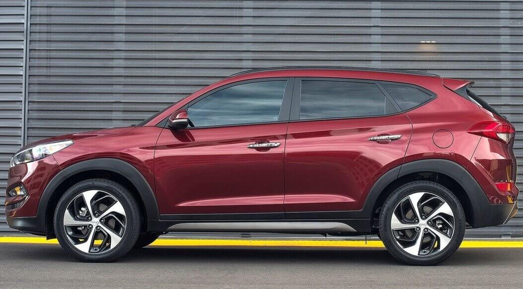 Foto mostrando a lateral esquerda de um Hyundai Tucson G3 vermelho estacionado.