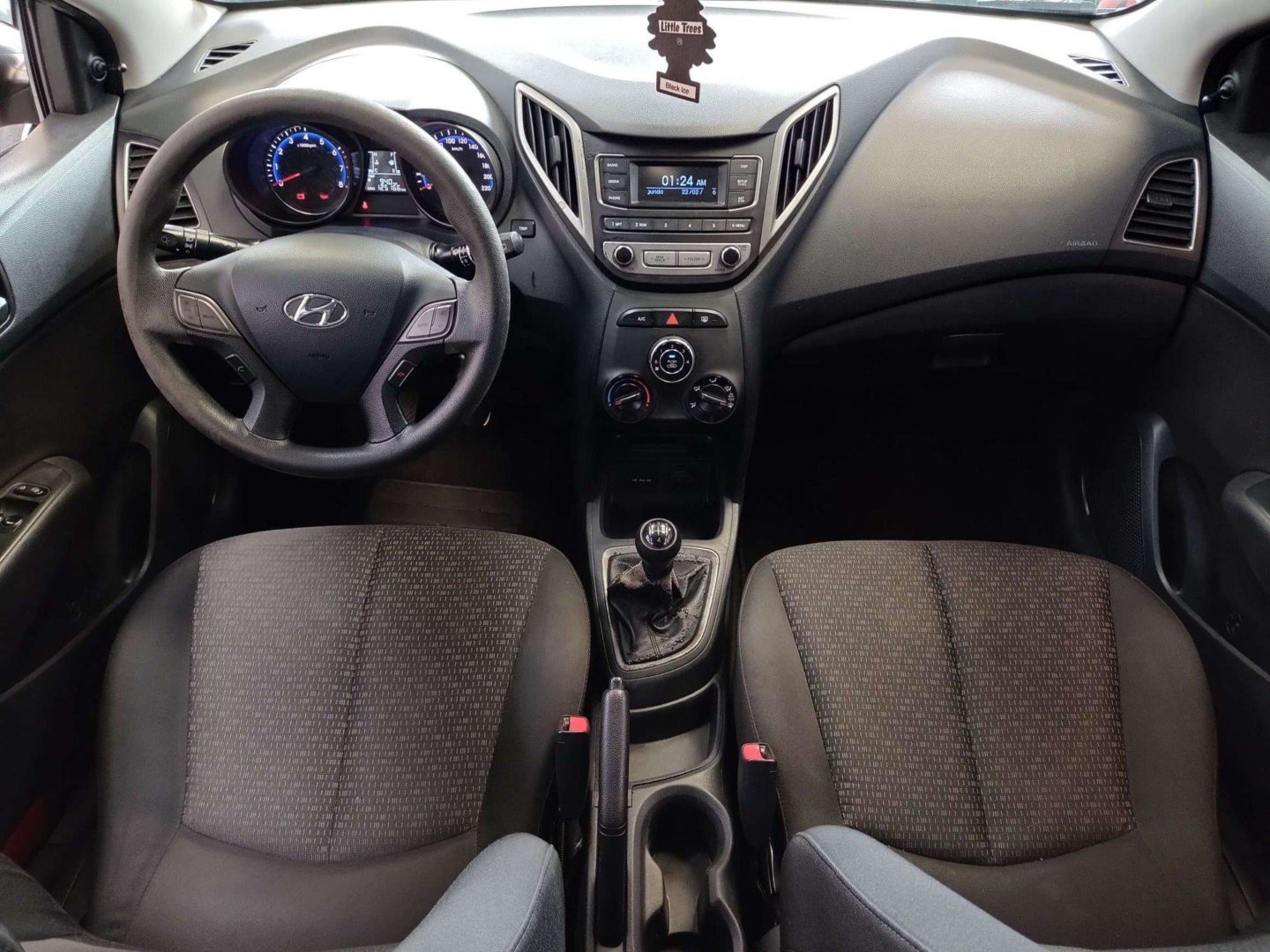 Foto do interior do Hyundai HB20, exibindo painel, central multimídia, parte dos bancos e da porta.