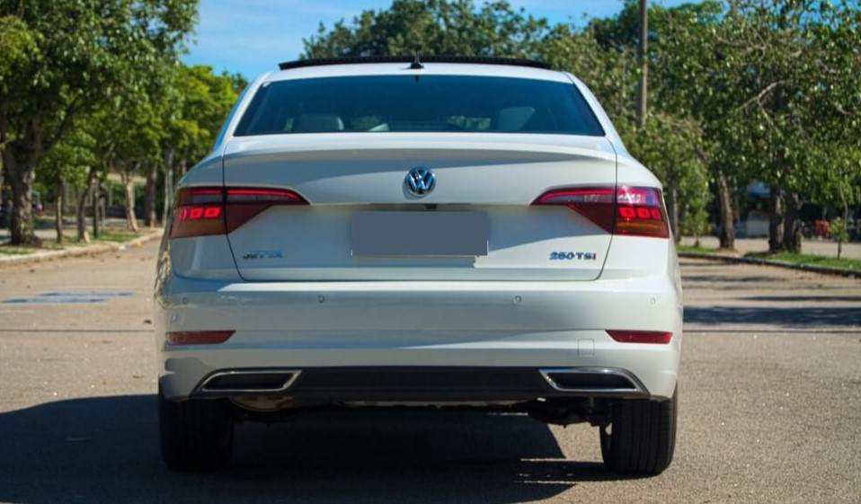 Foto mostrando a traseira de um Volkswagen Jetta G7 branco estacionado.