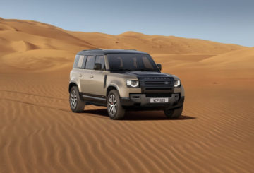 Foto do Land Rover Defender 110 PHEV de frente na areia, exibindo a dianteira e a lateral do passageiro.