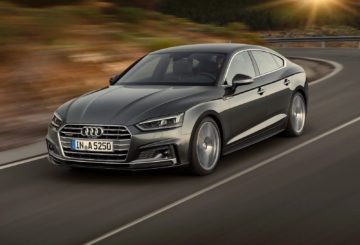 Foto da frente o Audi A5 Sportback S Line 2024 na estrada, exibindo a dianteira e a lateral do motorista.