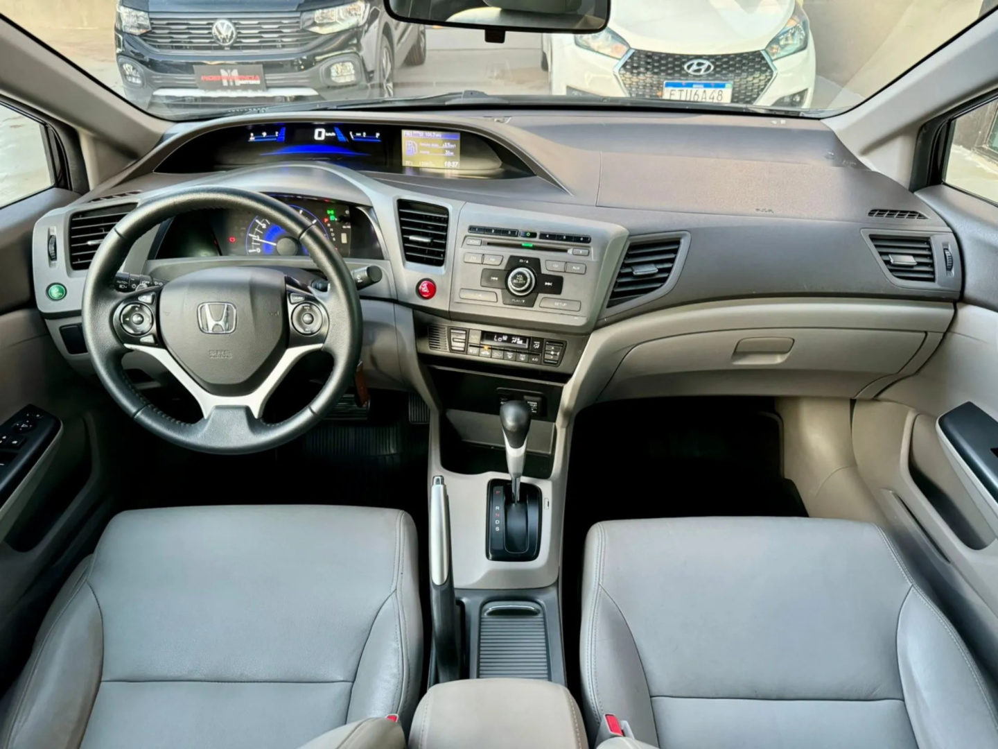 Foto interna do Honda Civic LXL 2011, exibindo o volante, painel de instrumentos, central multimídia, parte dos bancos e portas.
