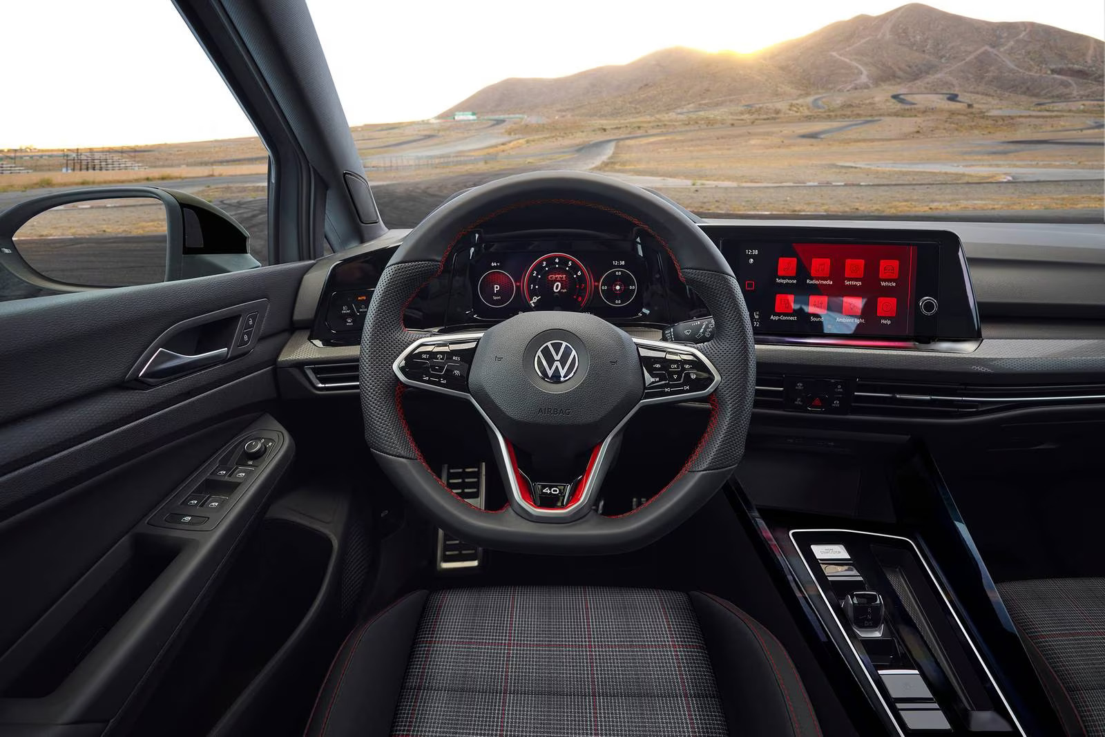 Foto interna do Volkswagen Golf GTI 2023, exibindo o painel de instrumentos, volante multifuncional e central multimídia.