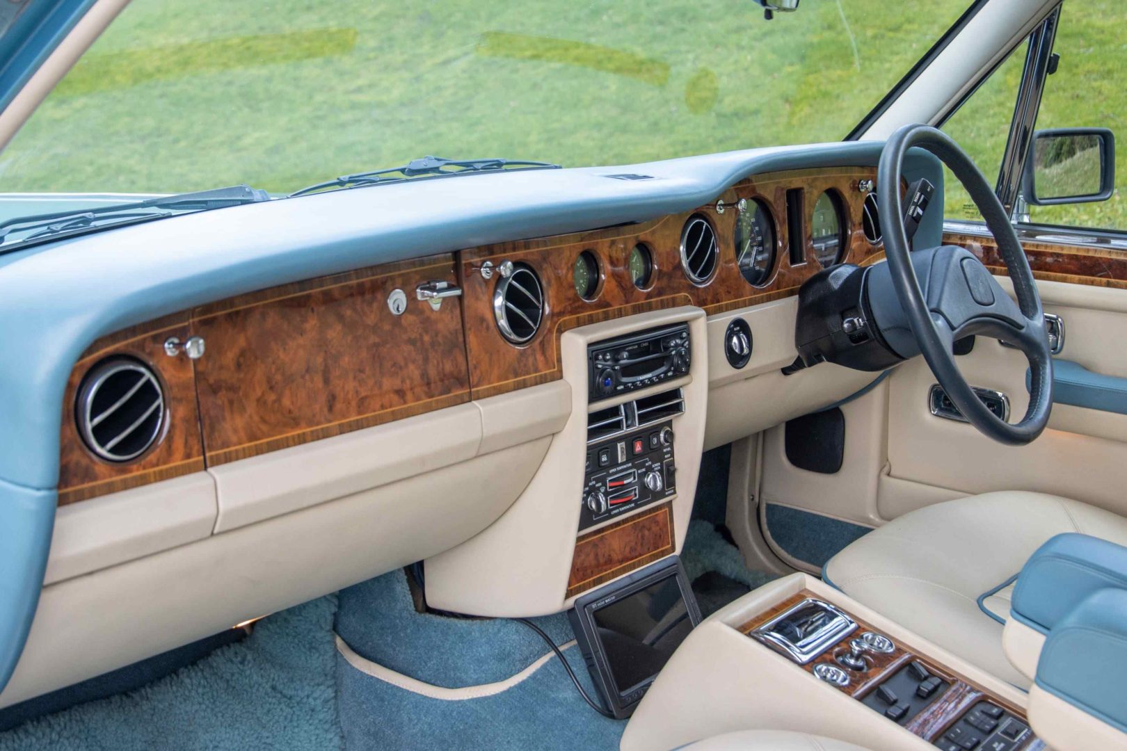 Foto interna do Rolls-Royce Silver Spirit 1991, exibindo todo o painel, volante console central e parte dos bancos.