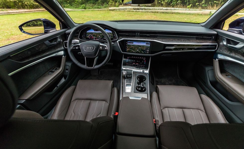 Foto interna do Audi A6 Performance Black Quattro 2022, exibindo painel de instrumentos digital, volante multifuncional, central multimídia, parte dos bancos e portas.