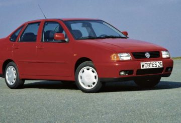 A imagem mostra o carro Volkswagen Polo Classic, com pintura na cor vermelha. Ele está parado em um local asfaltado.
