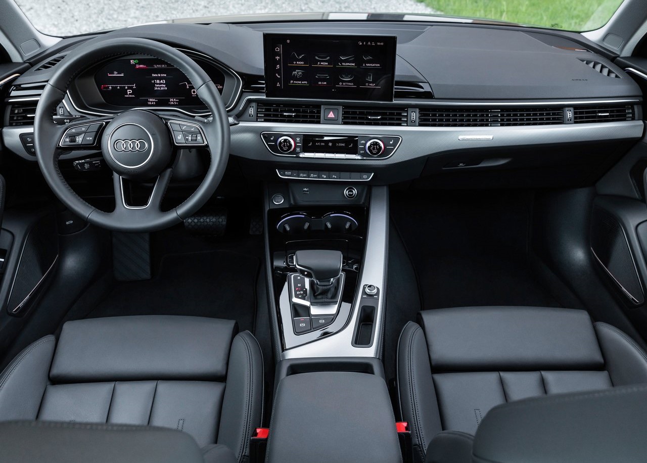 Foto interna do Audi A4 sedan 2022, exibindo o painel de instrumentos digital, volante multifuncional, central multimídia, parte do console central, bancos e portas.