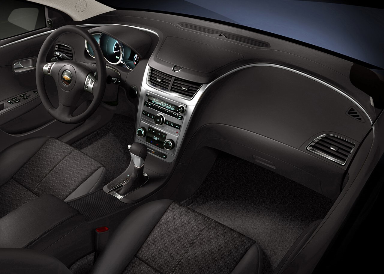 Foto interna do Chevrolet Malibu LTZ 2.4, exibindo parte do painel de instrumentos, volante multifuncional e o sistema de infotainment.